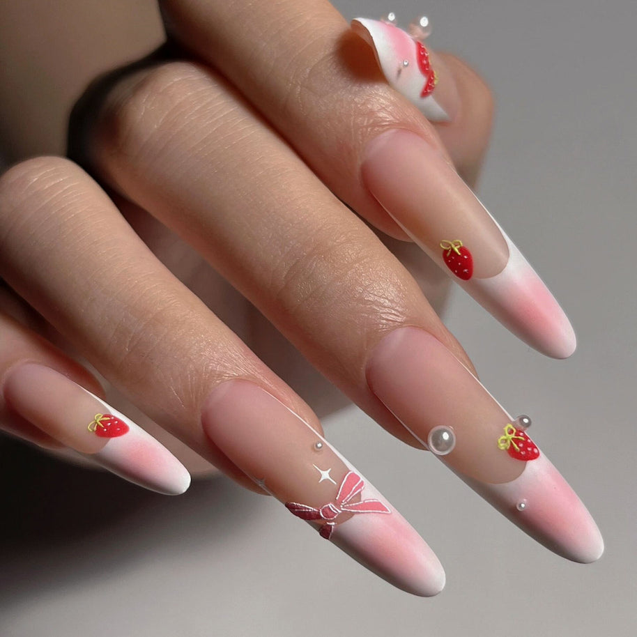 Matte extra-long stiletto nails with pink-nude gradient tips, decorated with hand-painted strawberries, bows, and pearls for a sweet, feminine vibe.
