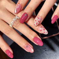 Oval-shaped press-on nails in rose pink, with glitter, petal print, and silver rhinestone details