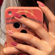 Oval-shaped press-on nails in rose pink, with glitter, petal print, and silver rhinestone details