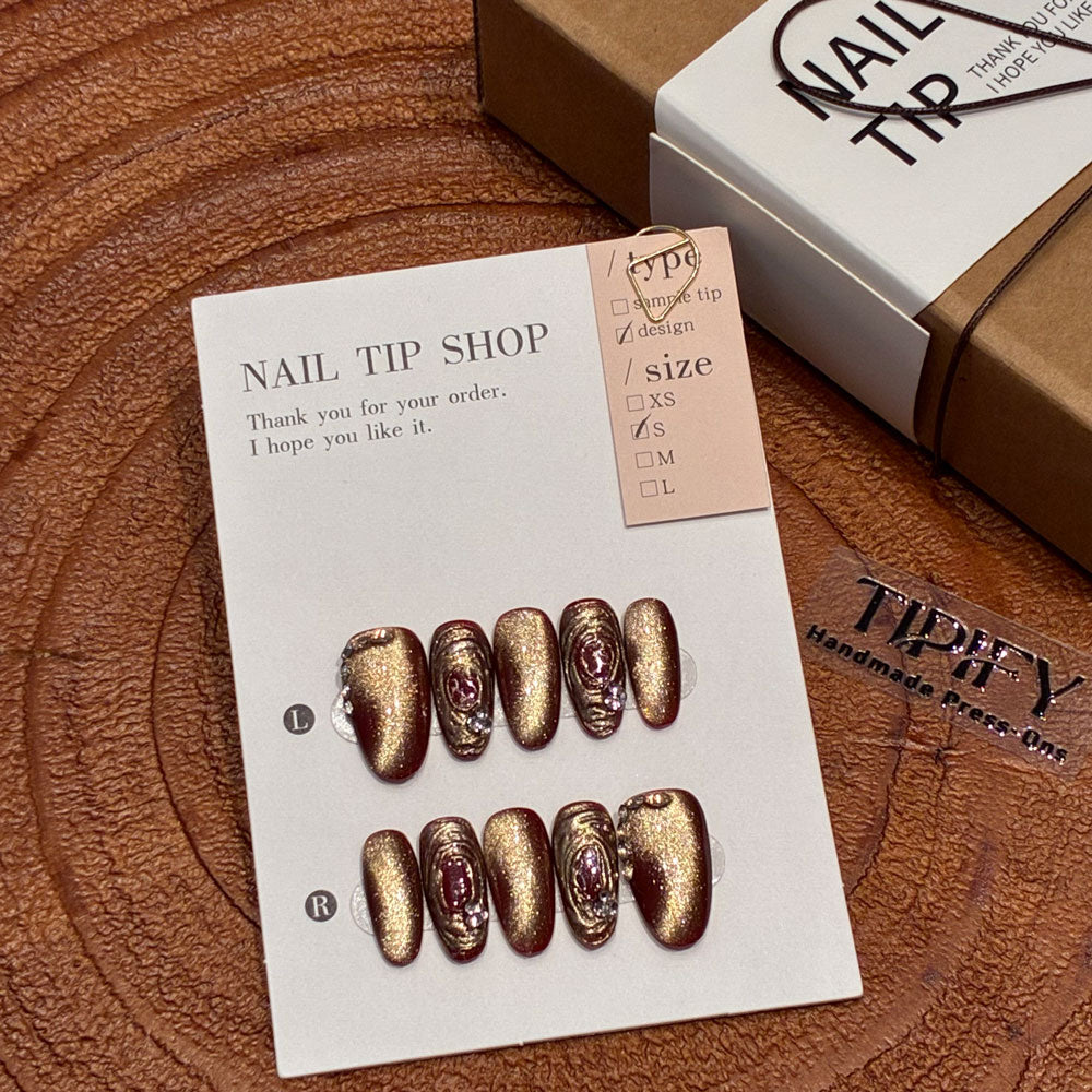 red gold cat eye press on nails, gilded swirl fake nails, medium almond shape acrylic nails, festive wedding nails, luxury handmade reusable nails, rhinestone accent nail art, 2026 Chinese New Year nails, women's daily wear fake nails