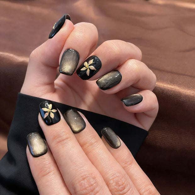 black gold floral cat eye press on nails, gilded flower accents fake nails, short square shape acrylic nails, dark luxury nail art, reusable edgy press on nails, party date fake nails, 2026 trendy black gold nails, women's bold fake nails