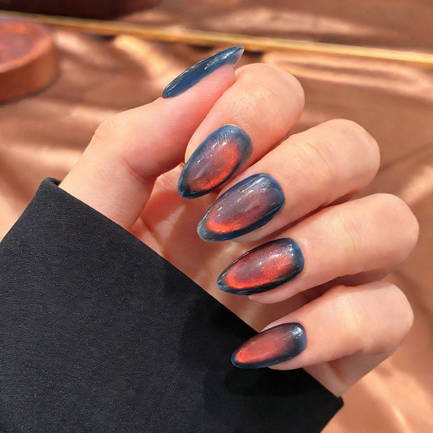 Deep blue press-on nails with a vivid red magnetic cat eye shimmer