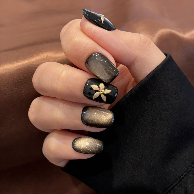black gold floral cat eye press on nails, gilded flower accents fake nails, short square shape acrylic nails, dark luxury nail art, reusable edgy press on nails, party date fake nails, 2026 trendy black gold nails, women's bold fake nails