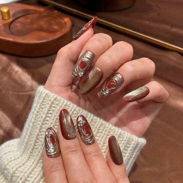 red gold cat eye press on nails, gilded swirl fake nails, medium almond shape acrylic nails, festive wedding nails, luxury handmade reusable nails, rhinestone accent nail art, 2026 Chinese New Year nails, women's daily wear fake nails